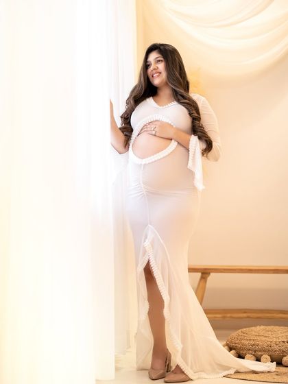 This elegant white gown features a sheer fabric that beautifully and tastefully shows off the baby bump.