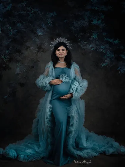 A moody and enchanting portrait. The dark, painterly backdrop makes this mom-to-be in her sea-green gown and crown look like a character from a fantasy story.