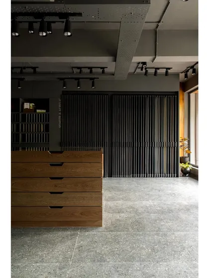 A wide view of the showroom's main floor, showing the clean lines of the custom furniture and the moody, industrial-inspired lighting and ceiling.