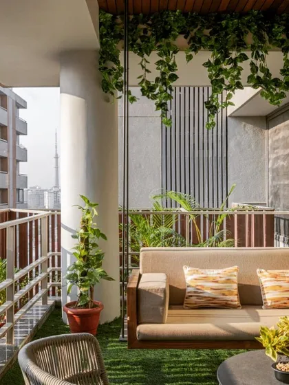 A hanging swing sofa is the ultimate statement piece for comfort and style. I integrated this cushioned swing into a modern balcony design with artificial grass flooring and a slatted privacy screen, creating a perfect nook for afternoon naps.