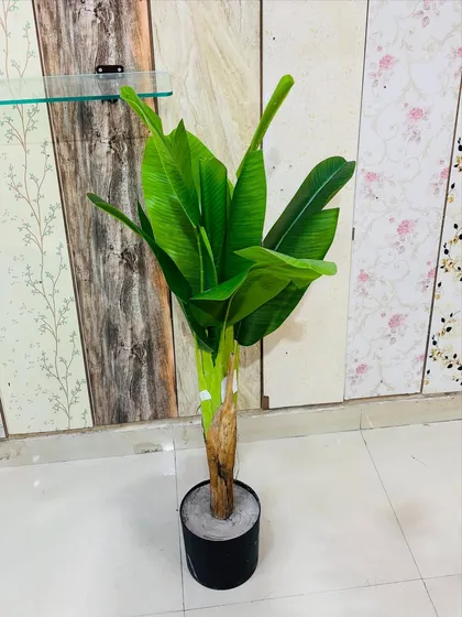 This artificial banana tree features a realistic, textured trunk and broad green leaves, perfect for themed decor.