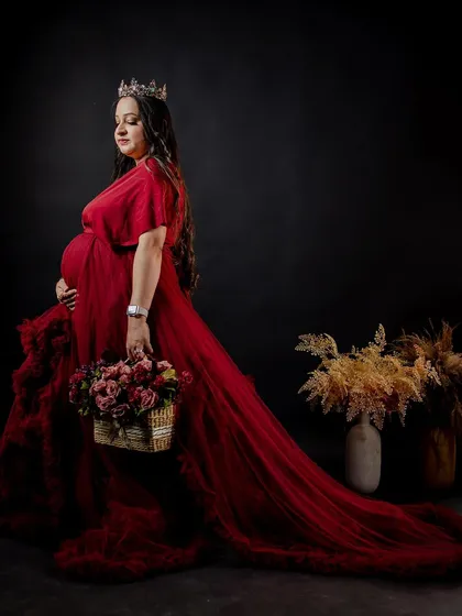 A beautiful side profile of the mother-to-be in her red gown, holding a basket of flowers. The makeup is elegant and timeless.