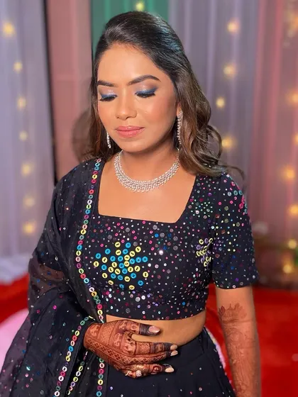A glamorous look for a Rajasthani-themed night. The bride's makeup features a dramatic blue smokey eye to match the colorful details on her black lehenga.