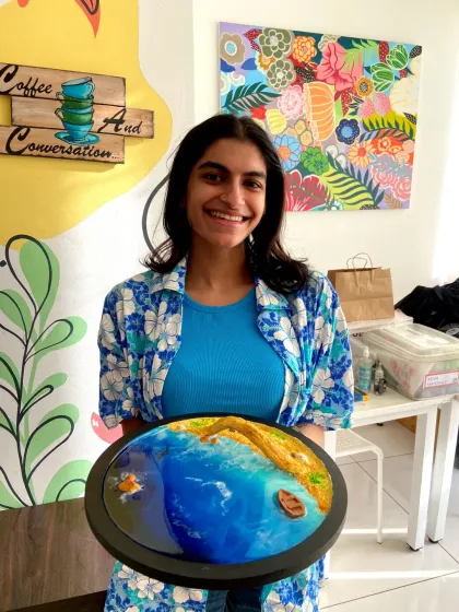 A participant with her finished resin beach art, featuring a bridge. This shows how you can add unique elements to your creation.