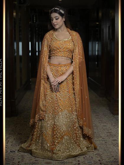A full-length view of our burnt orange lehenga with a cape-style dupatta. The rich color and timeless embroidery create a look of grace and glamour.
