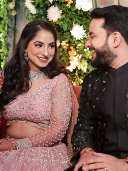 A happy, candid moment between the couple. The bride's soft pink lehenga and natural makeup look so pretty.