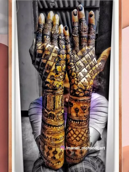 An artistic shot of a full-coverage bridal mehandi. The design is filled with dense checkerboard patterns on the back of the hands and intricate bands on the arms.