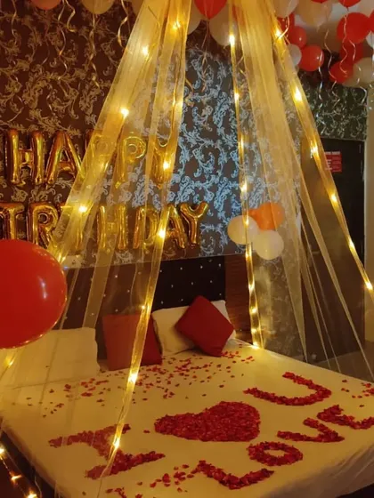 A romantic birthday surprise with a canopy tent illuminated by warm fairy lights. The "I Love You" message on the bed is made from fresh rose petals.