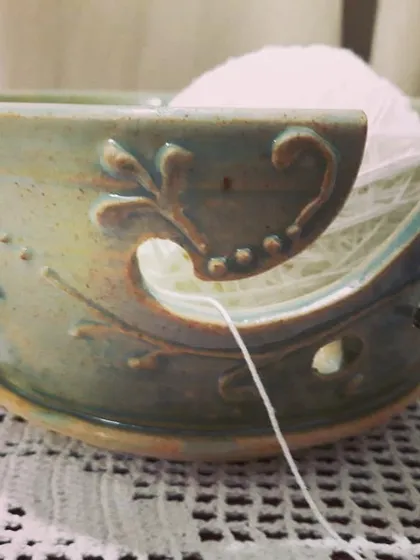 A happy knitter using their custom-made yarn bowl. I designed this piece with a special swirl to guide the yarn and decorative carvings, making it both a practical tool and a beautiful object for their craft corner.