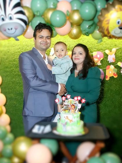 A family poses with their son's first birthday cake against a jungle-themed backdrop. We specialize in capturing the details of themed birthday parties.
