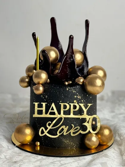 Celebrate a milestone 30th birthday with this stunning black and gold cake. It features a dark chocolate splash and a cascade of golden chocolate spheres.