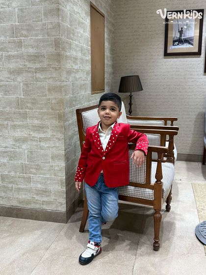 A casual pose in a not-so-casual jacket. The vibrant red velvet and polka-dot details make this a standout piece for any occasion.