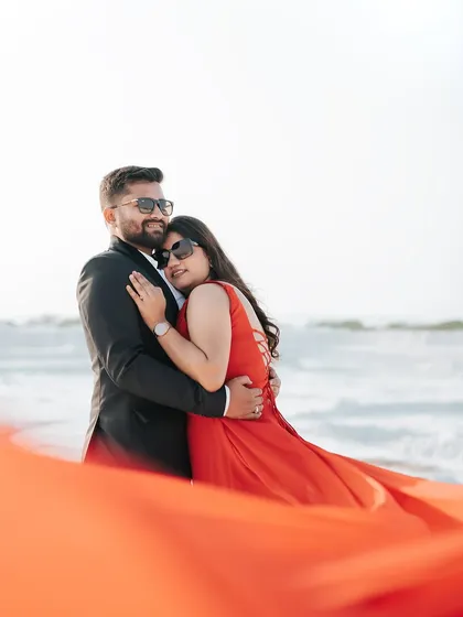 A romantic embrace by the water's edge at a quarry, with the bride's flowing red dress creating a stunning visual against the white terrain.