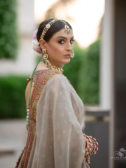 A regal side profile of the bride, Yashika. Her look is completed with a traditional nath, a statement matha patti, and a floral bun, creating a timeless and elegant silhouette.