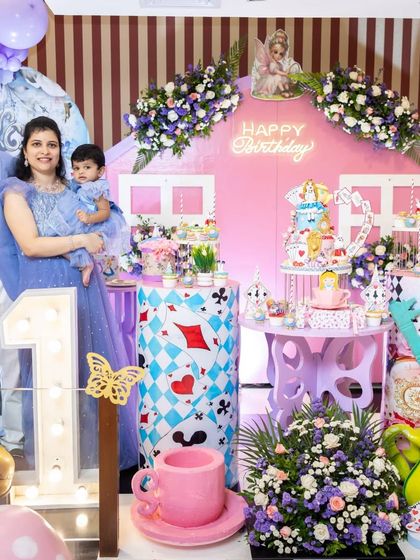It's always a joy to see the family enjoying the setup. This photo captures a happy moment with the birthday girl and her parents in front of the Wonderland-themed backdrop I created for her first birthday.