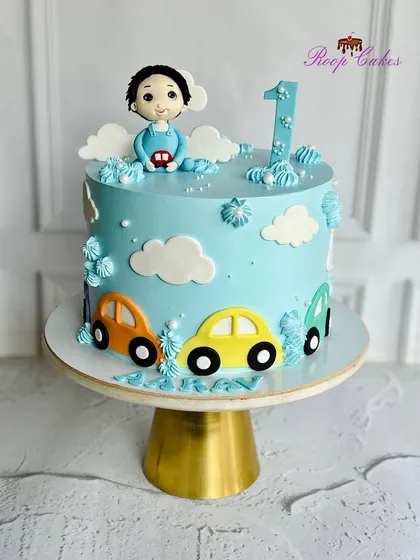 Fueled by frosting and full of fun. This first birthday cake is ready to roll with colorful cars and a cute fondant baby driver.