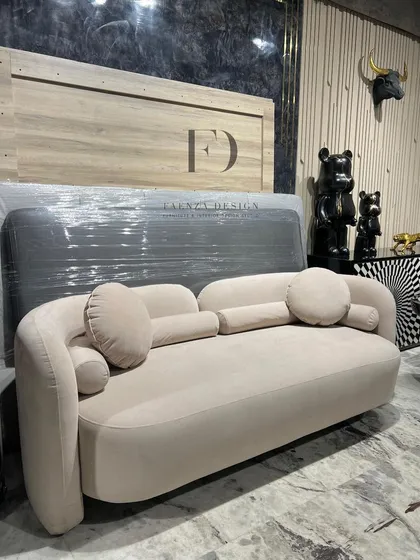 Different angles of a beautifully curved sofa in a neutral beige fabric. The soft, rounded forms and assortment of cylindrical and round cushions create an exceptionally comfortable and stylish seating experience.