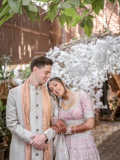 A tender moment as the bride rests her head on the groom's shoulder. This shot, taken in a rustic, beautifully decorated setting, is full of warmth and emotion.