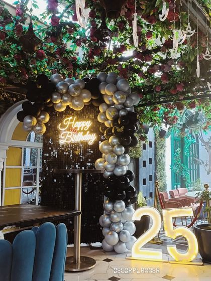 A gorgeous black and silver sequin backdrop at a cafe, perfect for a 25th birthday. The marquee numbers and neon sign create a fantastic photo opportunity and a central point for the celebration.