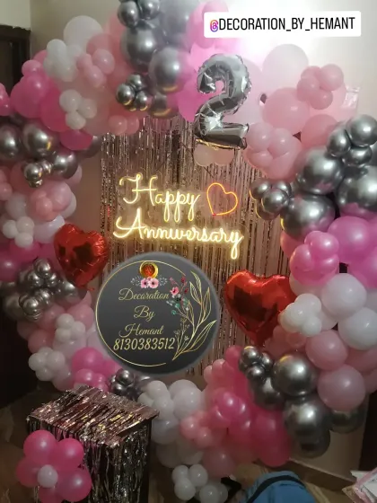 A vibrant 2nd-anniversary decoration. The ring is decorated with pink, white, and silver balloons, a neon sign, and heart-shaped foil balloons, making it a lovely setup for a couple's celebration at home.
