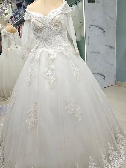 A full-length view of the off-the-shoulder embroidered ball gown. The floral lace appliqués cascade from the bodice down onto the voluminous tulle skirt.