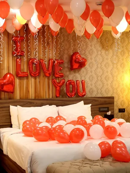 A classic romantic bedroom decoration. The bed is covered in red and white balloons, with "I LOVE YOU" foil letters on the wall, creating a simple yet powerful statement.