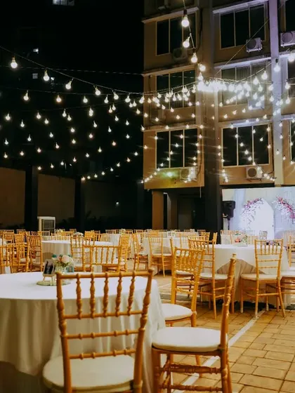 The party is ready for guests. This wide shot shows the elegant table settings under a sky of twinkling lights, creating an inviting and celebratory atmosphere.