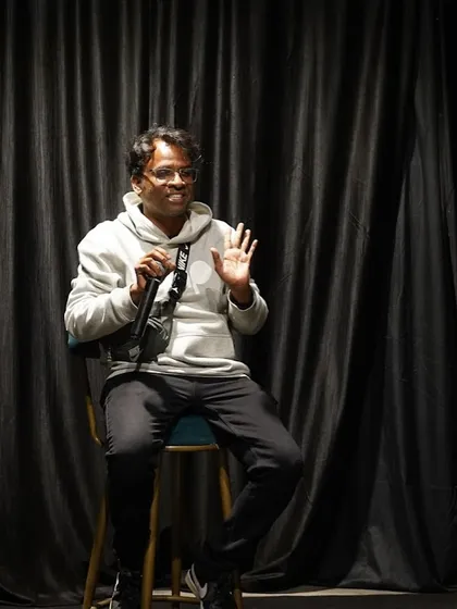 A participant shares his thoughts during a discussion or performance. The relaxed posture and engaged expression show the comfortable and interactive vibe of our events.