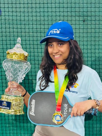A female champion holding her pickleball trophy and paddle. We are proud to create platforms where women athletes can excel and win.