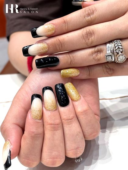 A glamorous combination of black and gold. This design features a mix of solid glossy black, sparkling gold glitter, and a modern French tip with a glittery nude base.