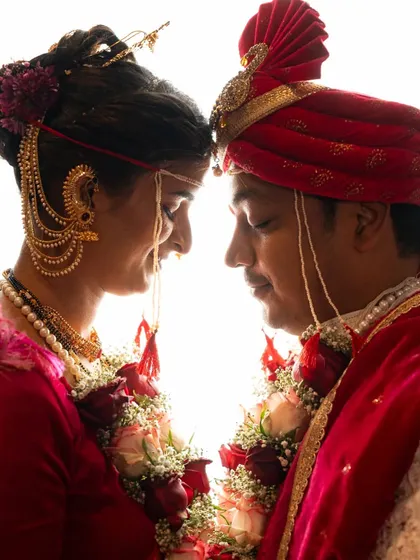 A beautifully backlit silhouette shot of a couple in their Maharashtrian wedding attire, creating a dramatic and artistic portrait.