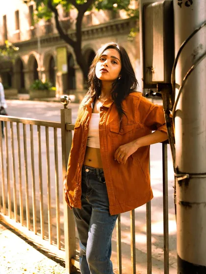 A classic street fashion pose, using a railing and a utility pole as props. It shows how to interact with the urban environment for great photos.