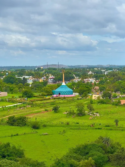 The peacock-domed Jain temple seen from a distance, nestled in the green landscape.