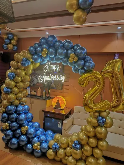 A sophisticated setup for a 21st anniversary celebration. We created a stunning balloon circle using metallic blue and gold balloons, complemented by a 'Happy Anniversary' neon sign and large foil numbers to mark the milestone.