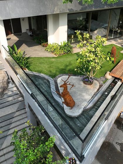 An artfully designed landscape at the entrance of a home, featuring a water body and a deer sculpture. The space is crafted to create a welcoming and memorable first impression.