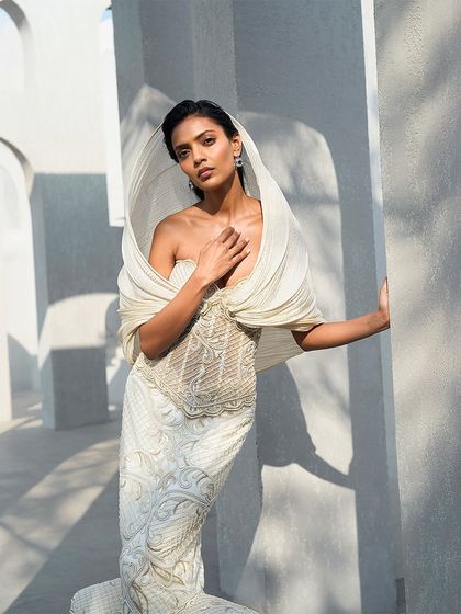 Tradition, retold through structure. This ivory gown features a sculpted hood and defined layers, sharpening heritage with modern tailoring while holding onto its roots.