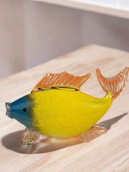 A sweet handblown glass fish with a yellow body and a blue head. Its simple, charming design makes it a lovely little piece of art for a bookshelf or side table.