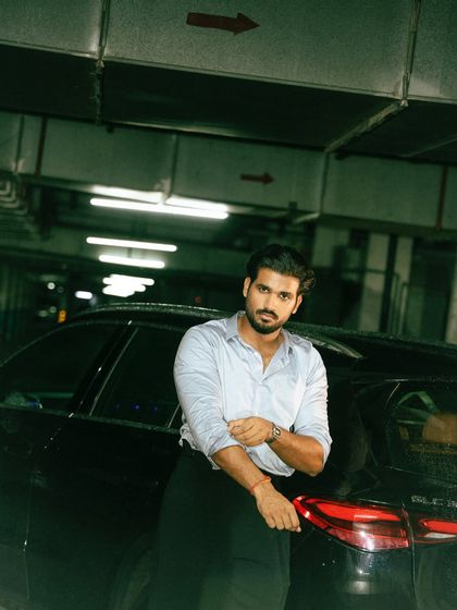 A confident portrait against a car, where the subject engages directly with the camera. The cool tones and industrial background add to the modern, urban feel.