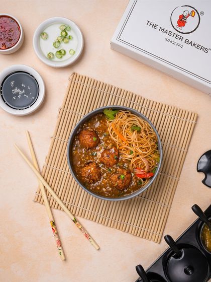 The classic combo of Vegetable Manchurian with gravy and Hakka Noodles. The savory manchurian balls are served in a rich sauce over a bed of stir-fried noodles.