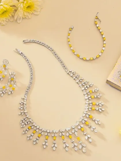 A beautiful flatlay of a fine jewellery set. We styled the necklace, earrings, and bracelet on a neutral background with a book and fresh yellow flowers to create an elegant and timeless composition.