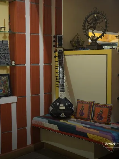 A corner dedicated to art and music, featuring a sitar, traditional Indian brass lamps (diyas), and other artifacts. This space is a personal gallery that reflects the cultural identity of the homeowners.