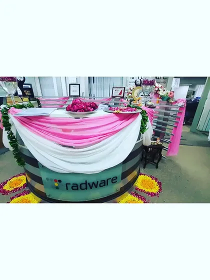 The fully decorated reception desk at Radware, featuring fabric drapes, flower petal trays, and small arrangements. This setup ensures the festive theme is front and center.