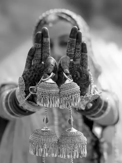 A creative black and white shot focusing on the bride's kalire, held up in her mehndi-covered hands.