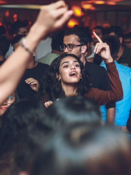 A guest with her hand up, lost in the music. This is the sign of a successful night where the music has truly connected with the audience.