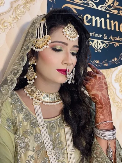 A classic Muslim bridal look with green and gold eyeshadow, a bold red lip, and traditional jewelry like a passa and nath. The makeup is designed to be elegant and photograph beautifully.
