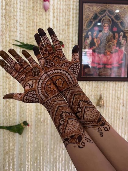 The semi-bridal mehendi is shown in a traditional setting, with a deity's picture in the background, adding to the auspicious feel.