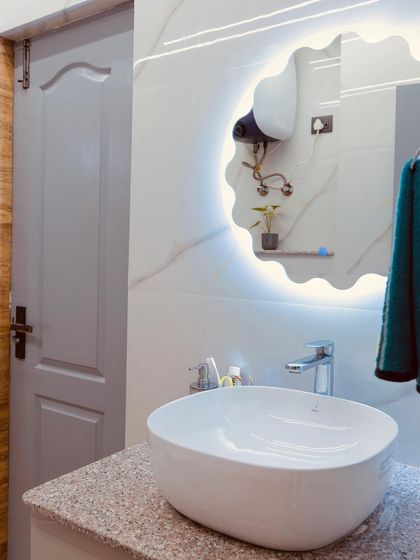 A stylish bathroom vanity setup with a unique wavy backlit mirror and a modern vessel sink.
