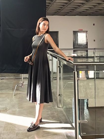 The model on a break between takes. This shot captures the scale of the production, with the large black screen used for lighting control visible in the background.