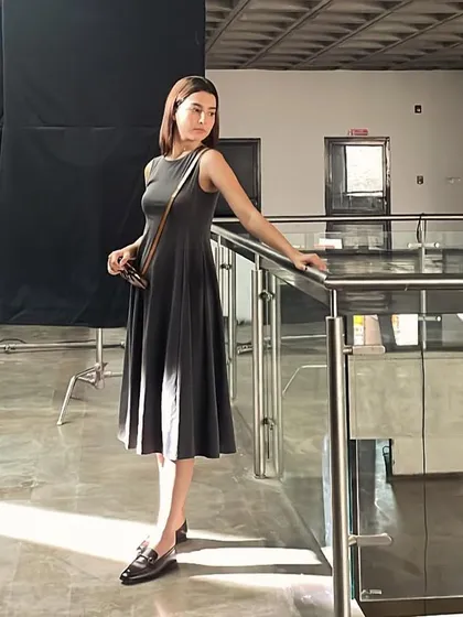 The model on a break between takes. This shot captures the scale of the production, with the large black screen used for lighting control visible in the background.