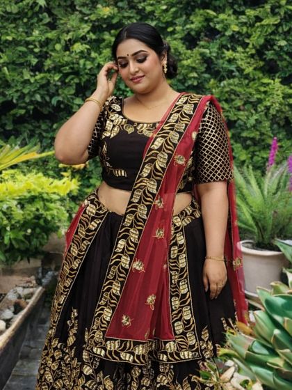 A closer look at the black and gold plus-size lehenga, showing the intricate blouse details and the beautiful drape of the red and gold dupatta.